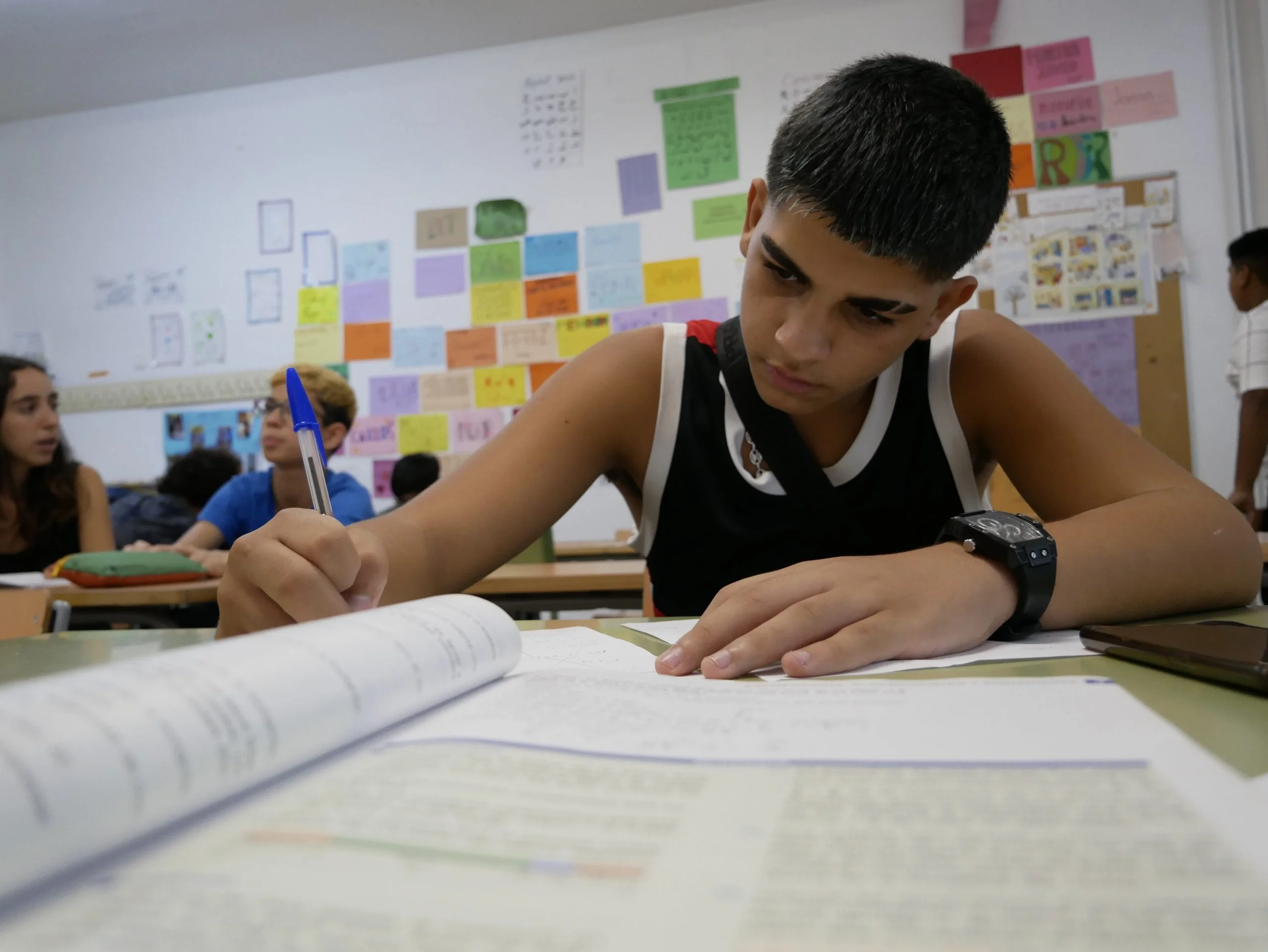 Un noi adolescent escrivint en una fulla blanca sobre Abordatge d’absentisme a Sant Roc - Badalona