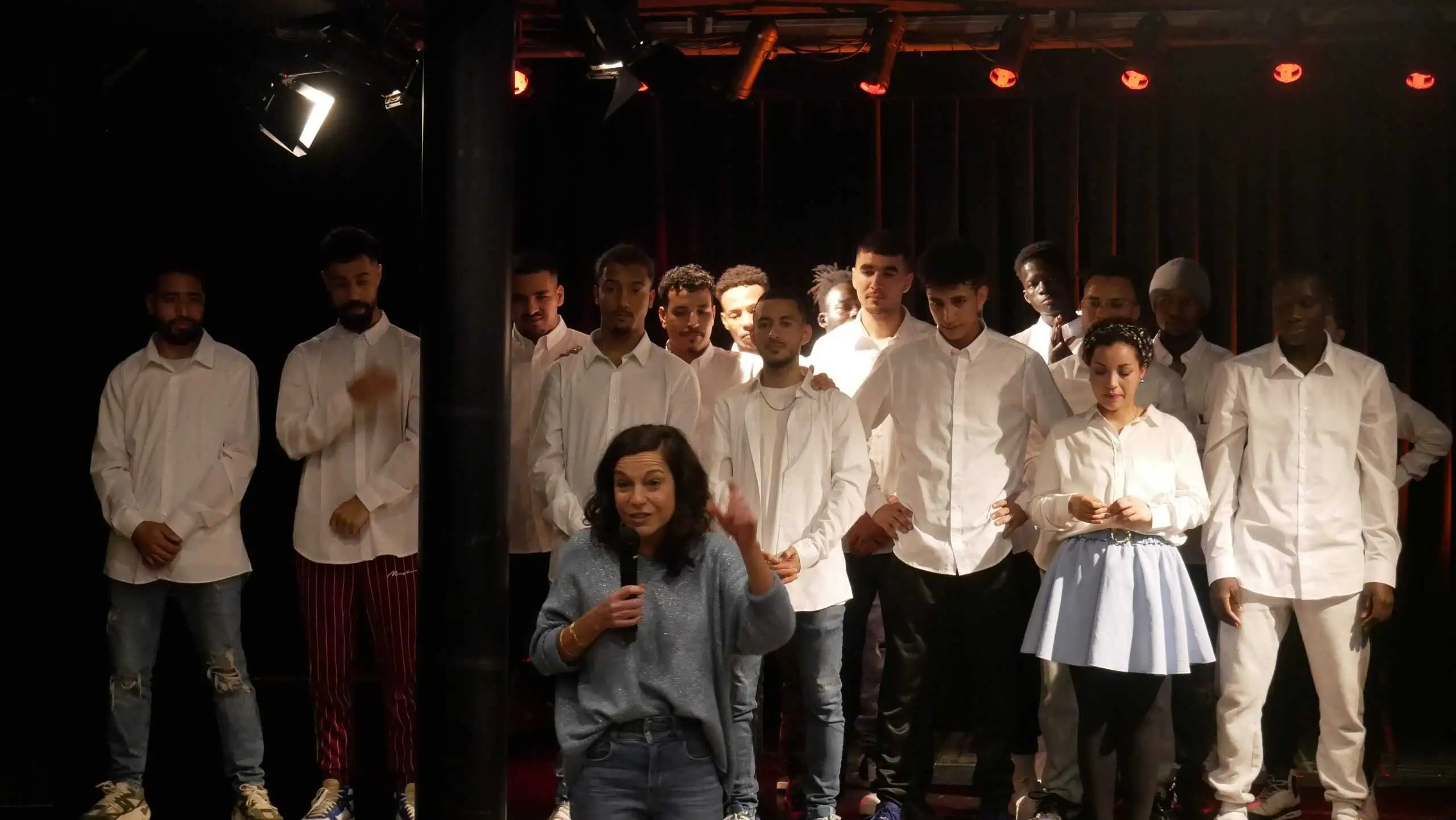 Actors i actrius damnunt de l'escenari, vestits amb camises blanques.