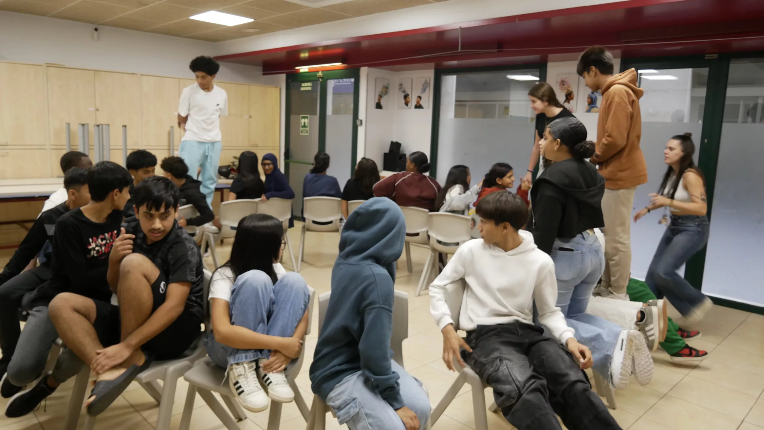 Joves en Activitat en la sala amb cadires en rotllana.