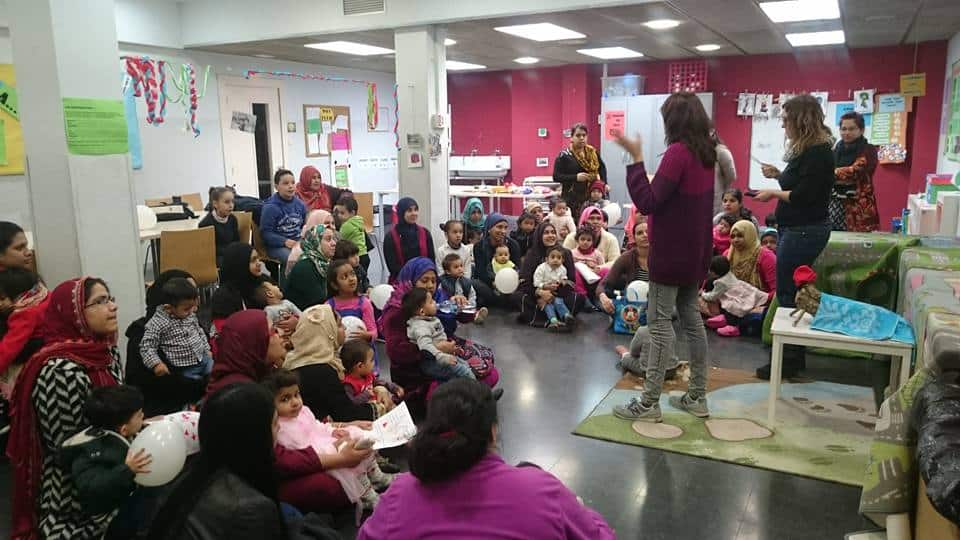 Mares i fills assegudes al terra escoltant a les educadores