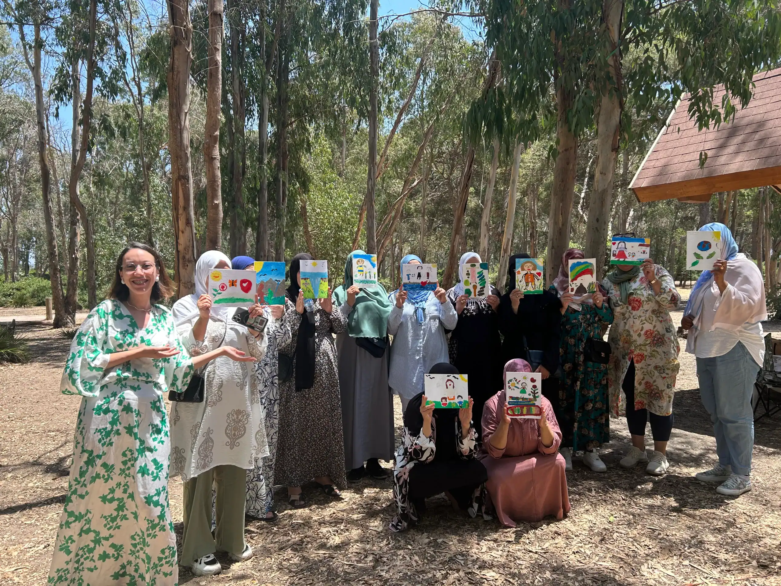 Dones en un bosc ensenyant els seus dibuixos.