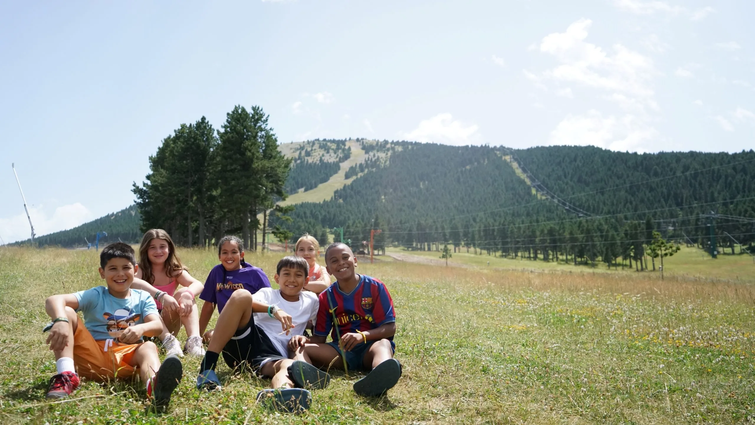 Nens i nenes asseguts en el sòl prop d'una muntanya en la naturalesa.