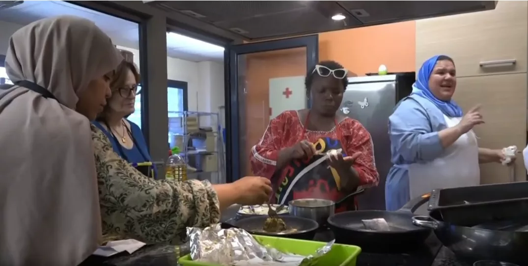 Quatre dones cuinen juntes en una cuina.