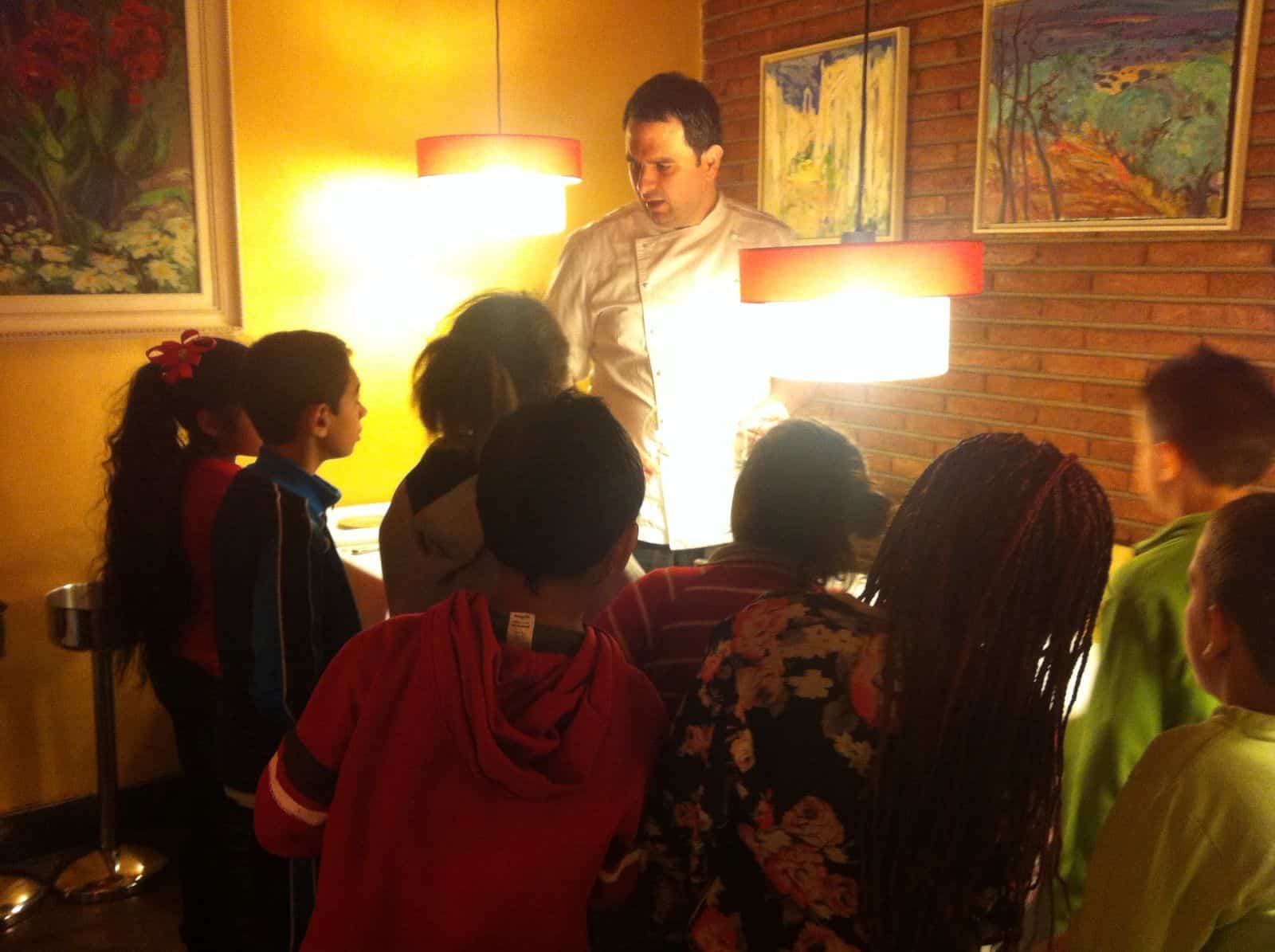 Un cuiner està fent una explicació a un grup de nens i nenes a un restaurant.