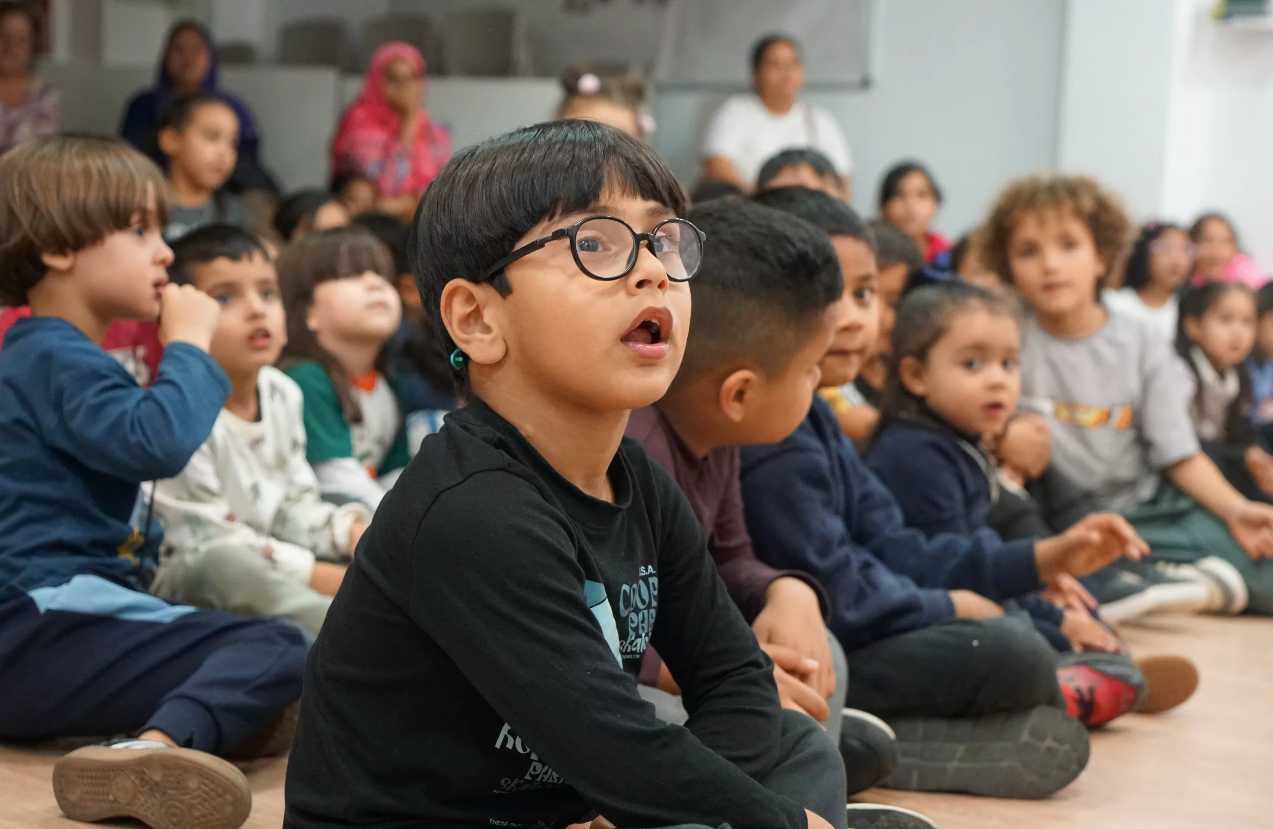 Nens i nenes asseguts al sòl durant una activitat.