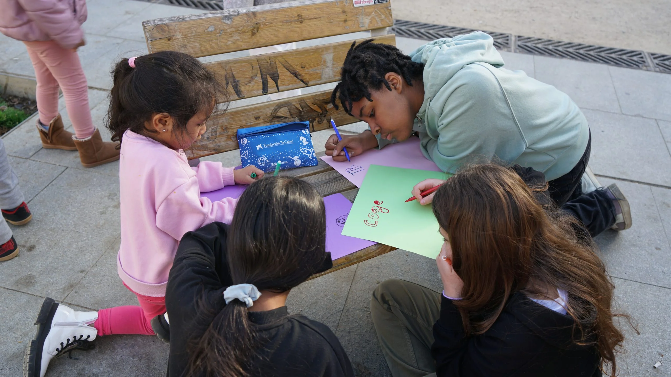 Nenes escrivint en cartolines de colors amb retoladors durant una activitat. Centre Obert Raval