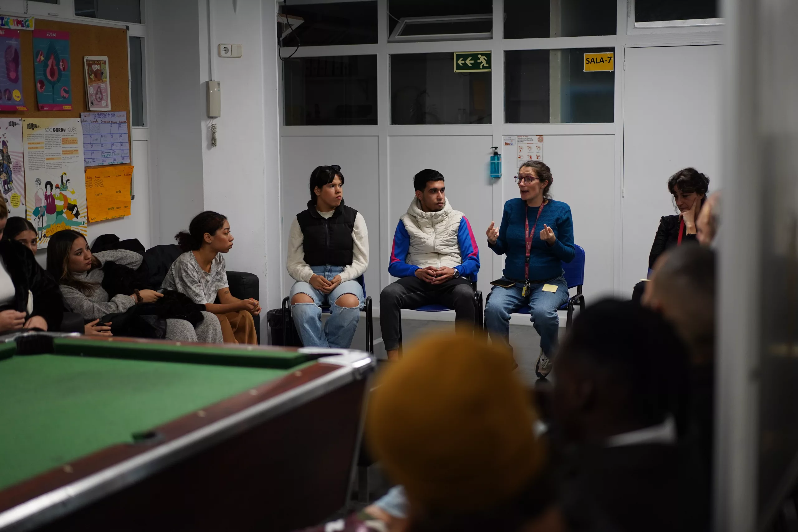 Joves entre 18 i 23 anys amb una educadora parlant de la vulnerabilitat social.