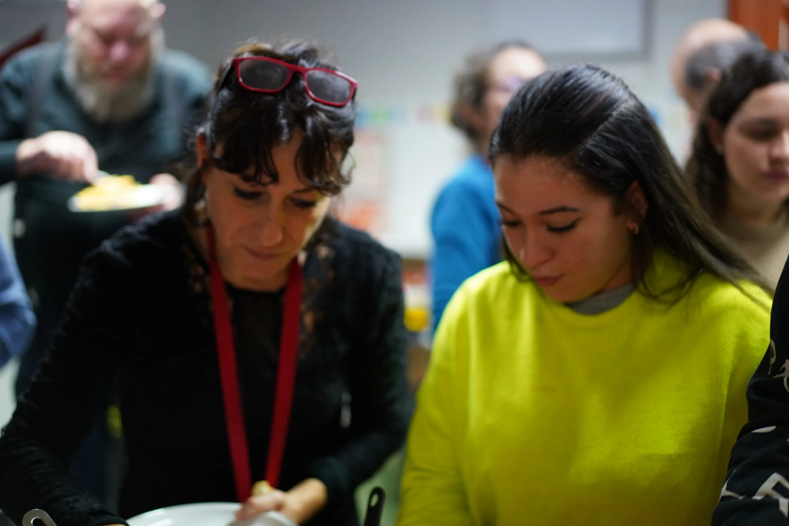 2 noies i més gents compartint menjar després d'una assemblea. Habitatges d'inclusió social