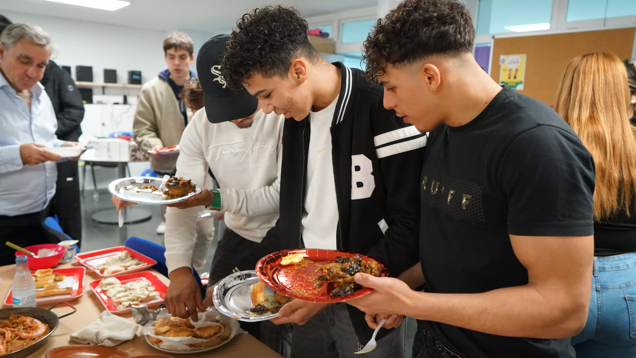 Nois al voltant d'una taula es serveixen el plat amb menjar.