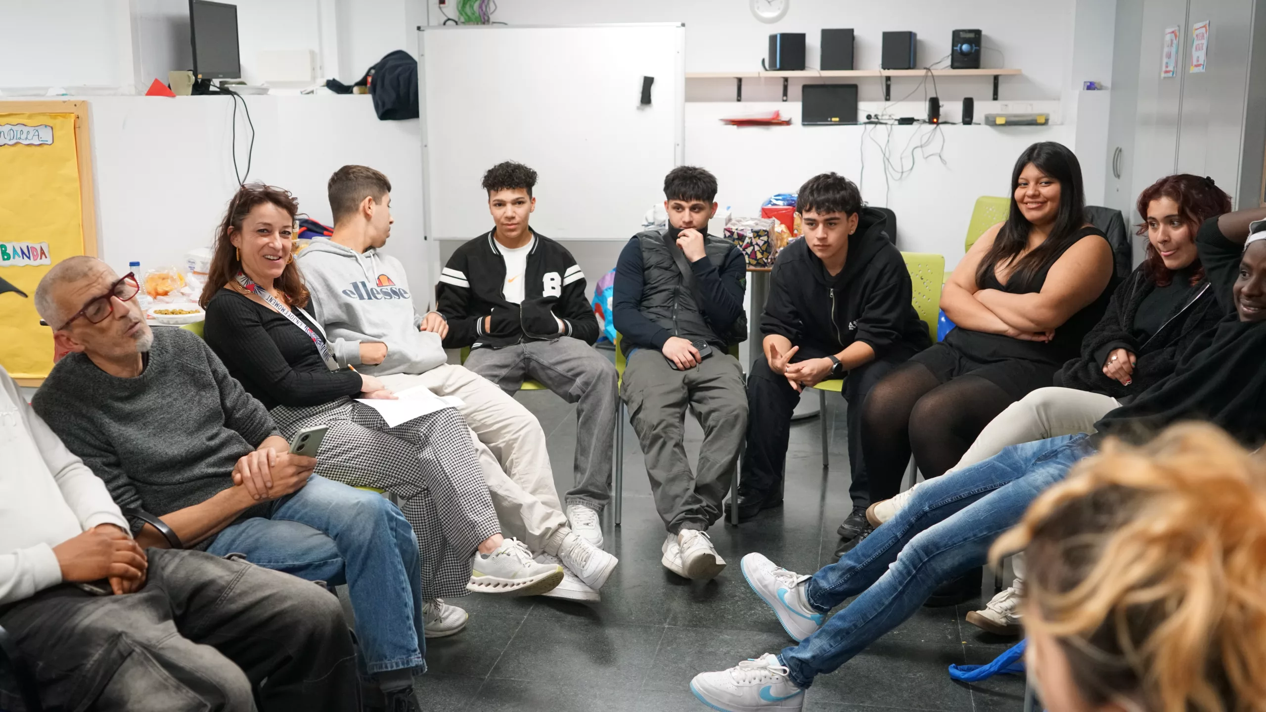 Nois i noies asseguts en cadires fent rollana. en un moment de parlar de la vulnerabilitat social en Casal amb educadors.