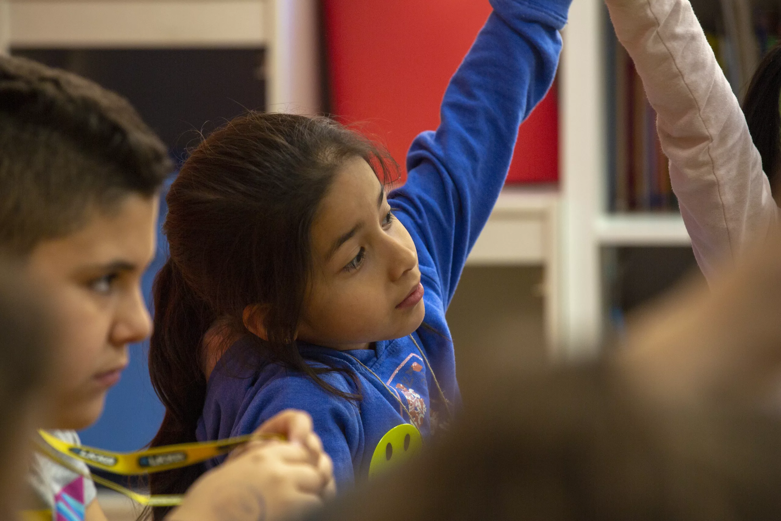 Nen i una nena amb braços aixecats en una sala del Casal.