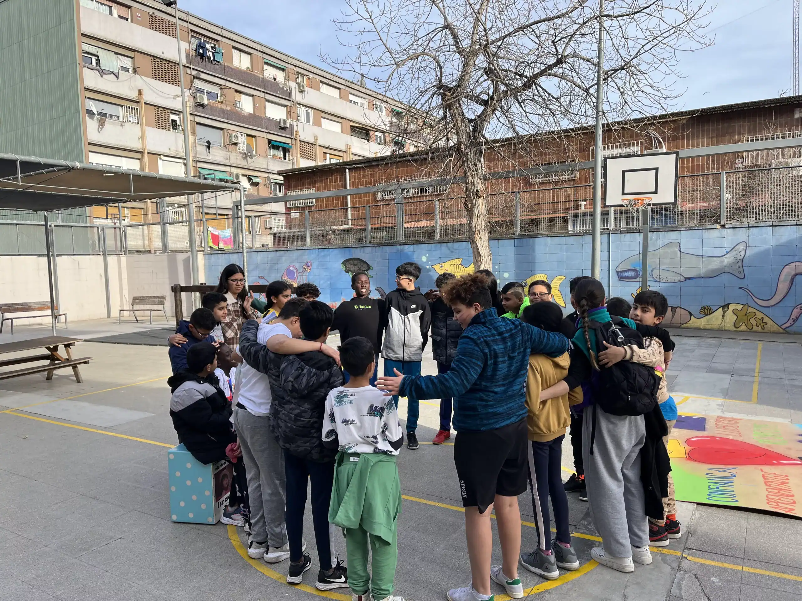 Nens i nenes fent rotllana de peu al pati d'una escola.