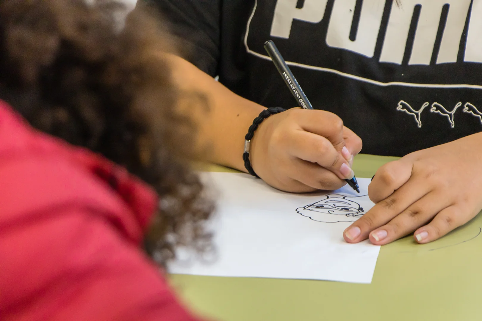 Una persona dibuixa en una fulla blanca amb un retolador negre. Projecte Cims