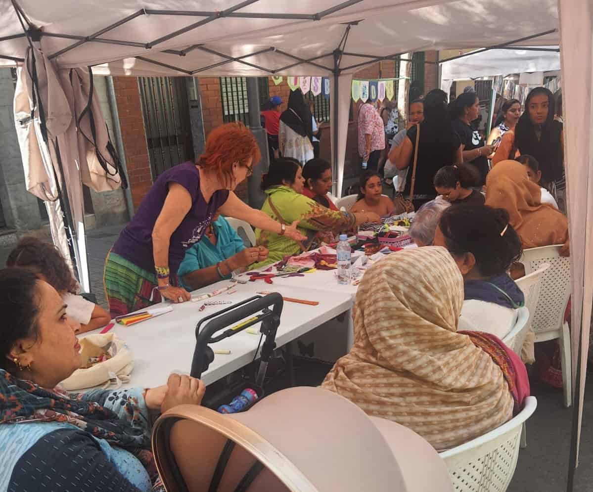 Dones participen en un taller de costura durant les festes majors del barri.