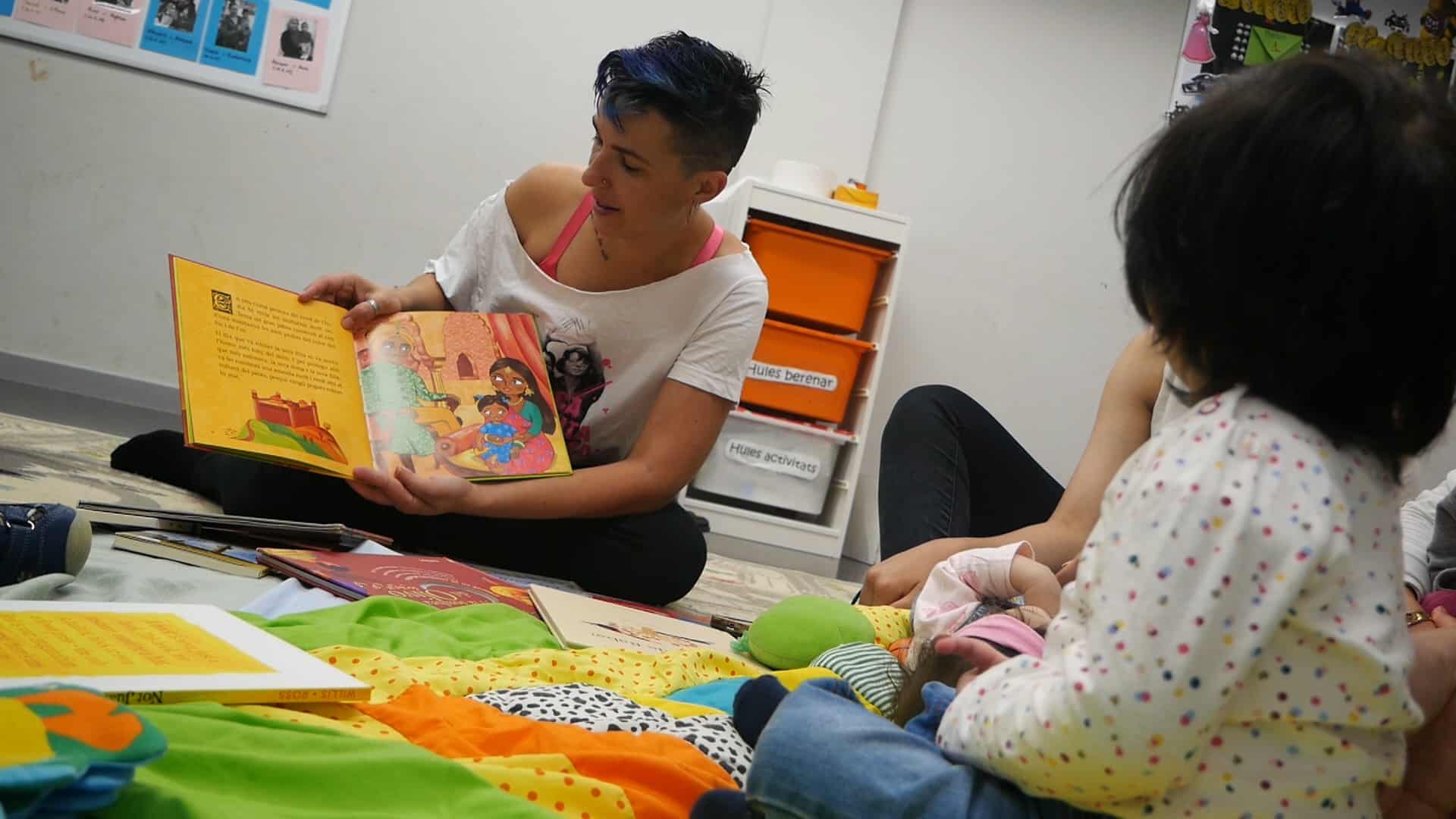 Educadora llegint un conte a un infant al terra