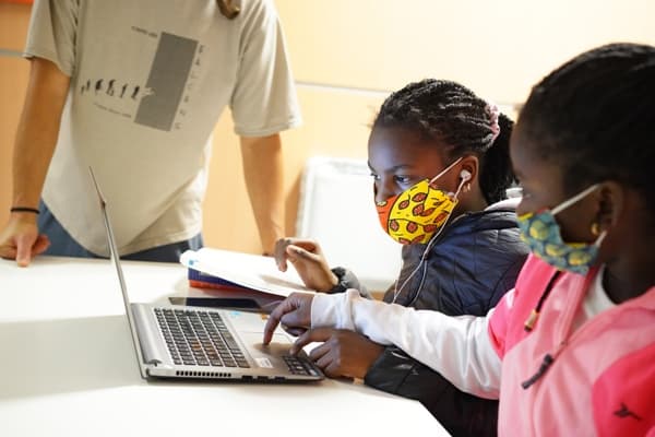 Dues infants amb mascareta utilitzant un ordinador portàtil