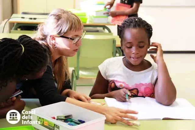 voluntaria ajudant a nena a fer els deures