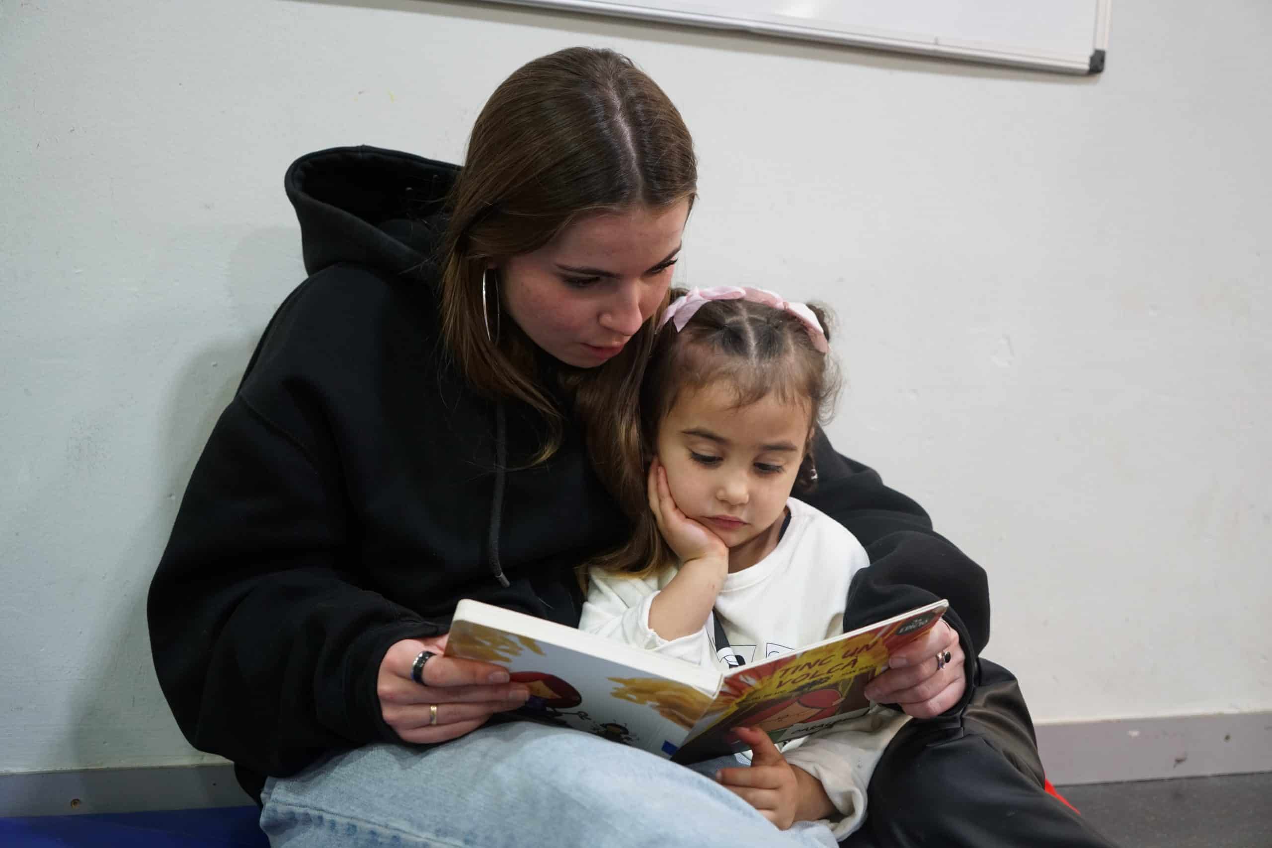 Noia ajudant a una nena a llegir