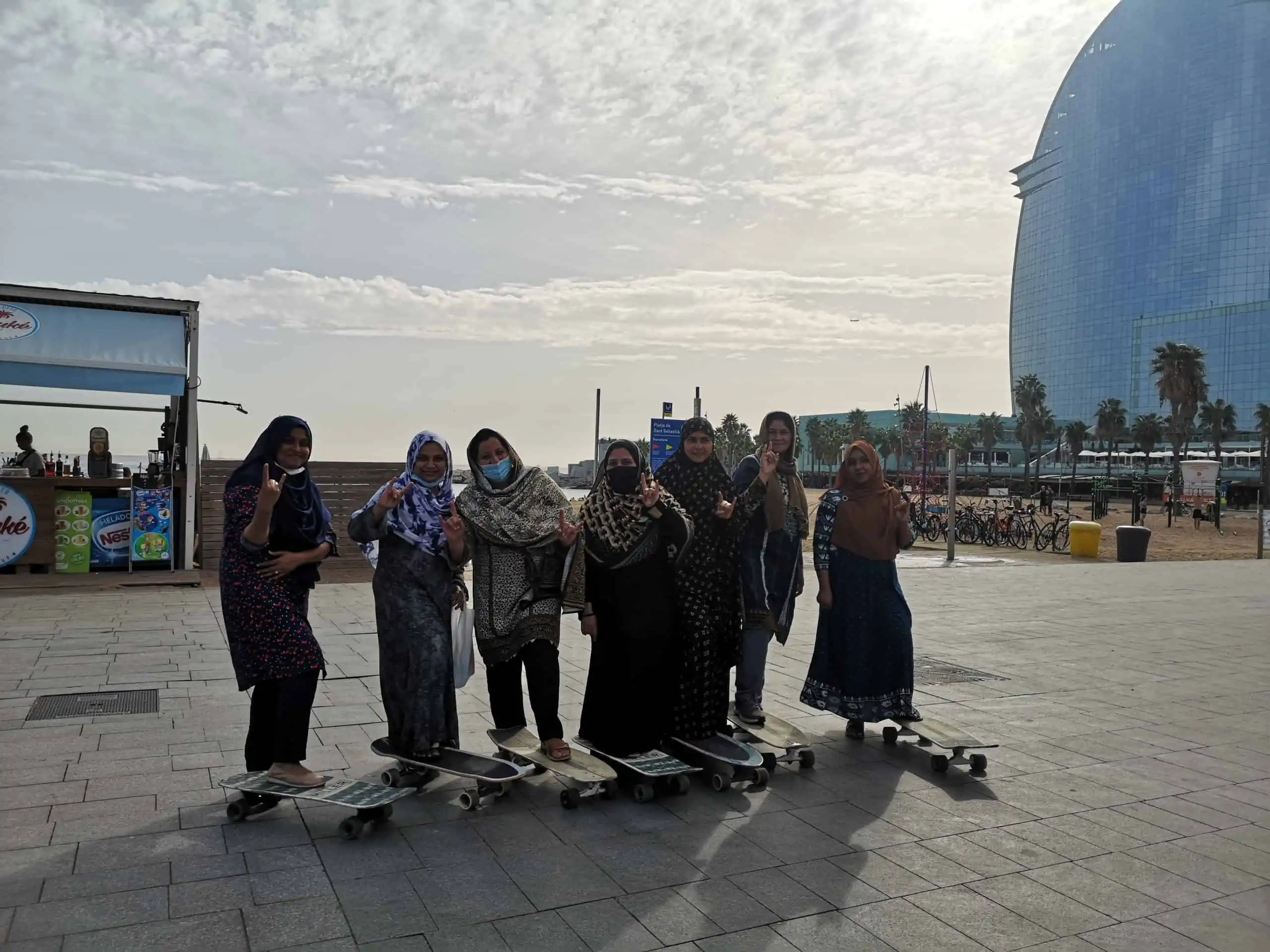Les participants de l'espai Dona del Raval amb longboards a la passeig marítim de Barcelona.
