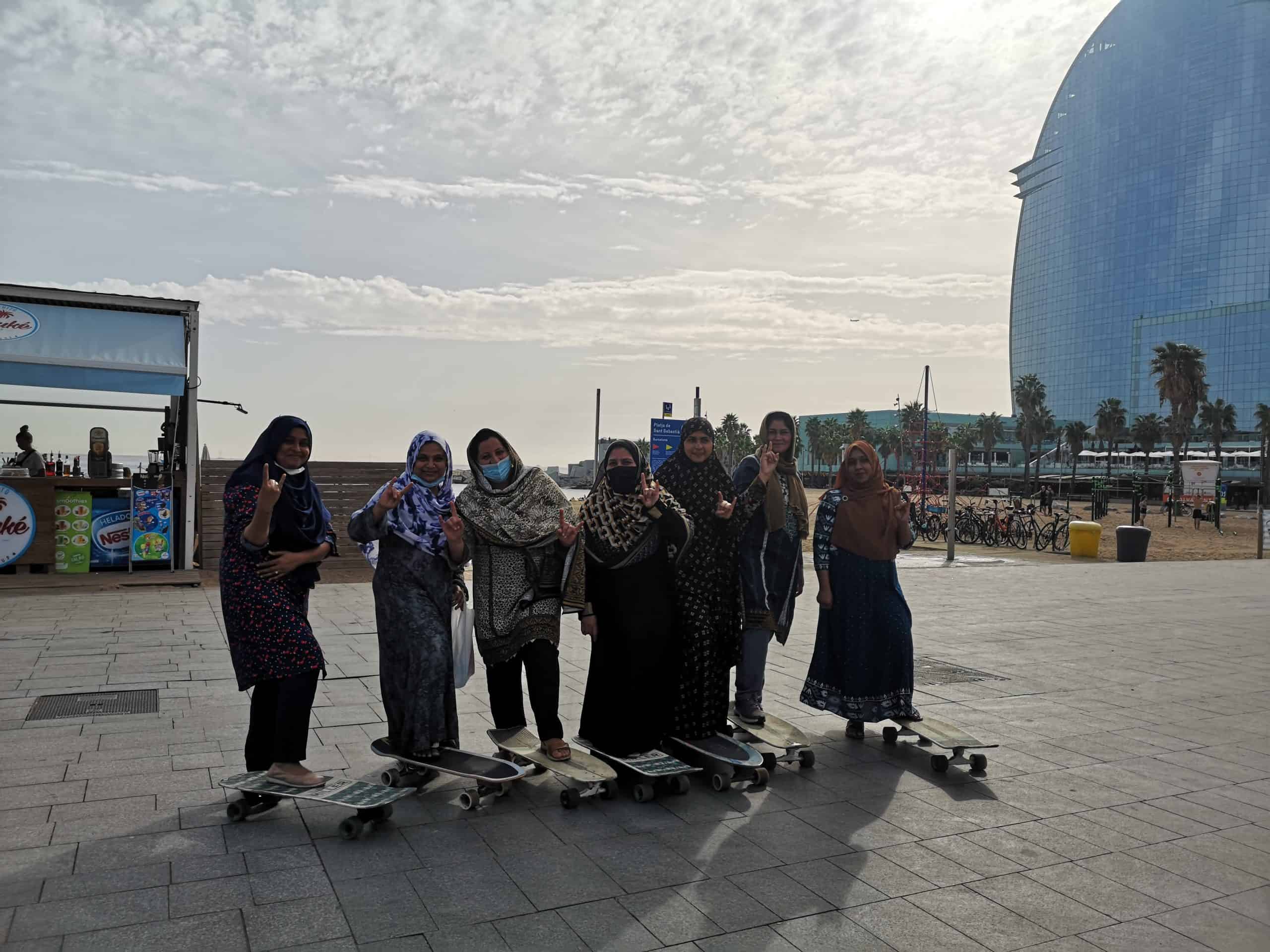 Les participants de l'espai Dona del Raval amb longboards a la passeig marítim de Barcelona.