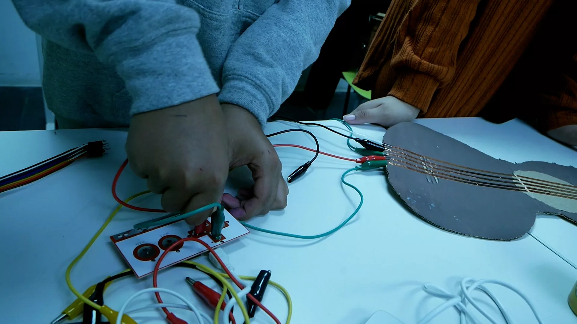 Dues mans connectant cables de diferents colors a una placa electrònica.