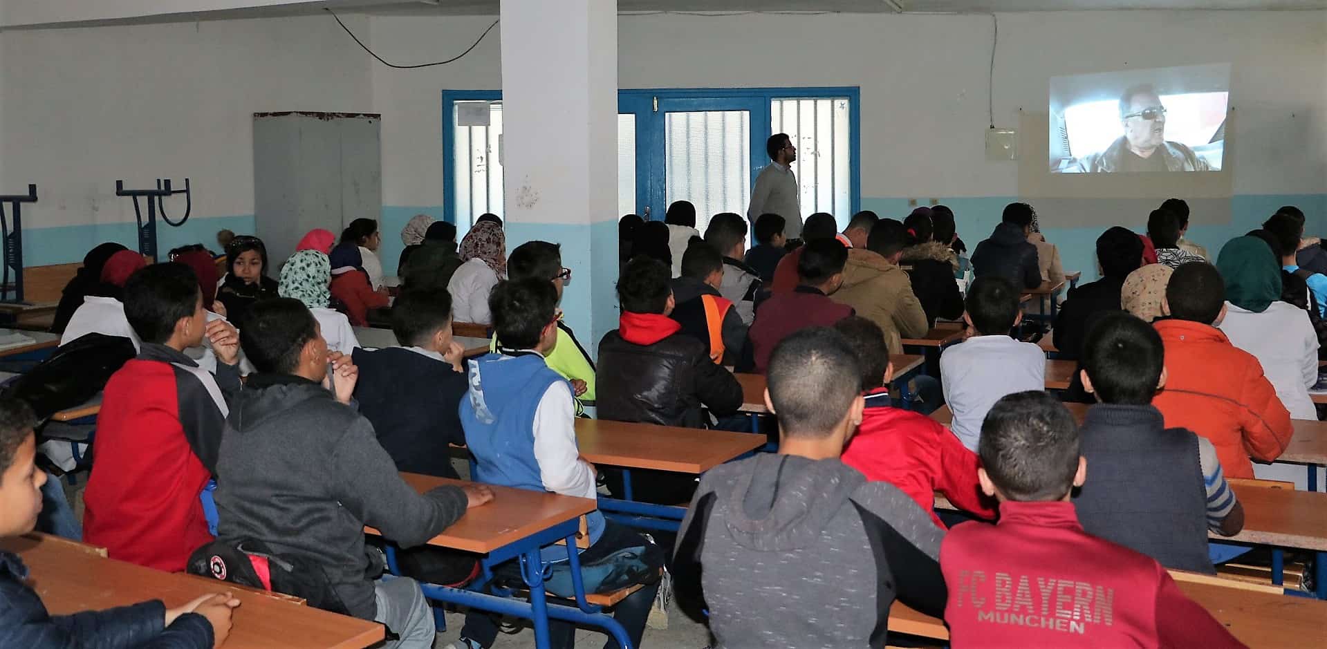 Foto d'un aula amb nois i noies participants del projcte Kalima al Marroc mirant un video amb el seu professor/educador.