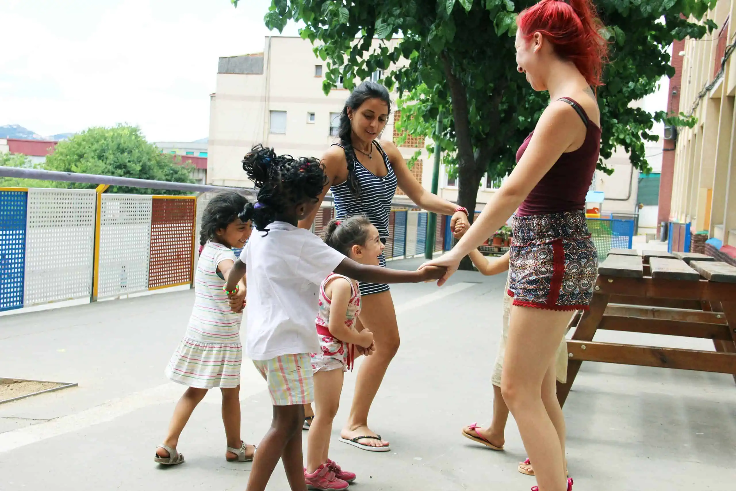 Nenes juguen amb monitores de menjador en un pati