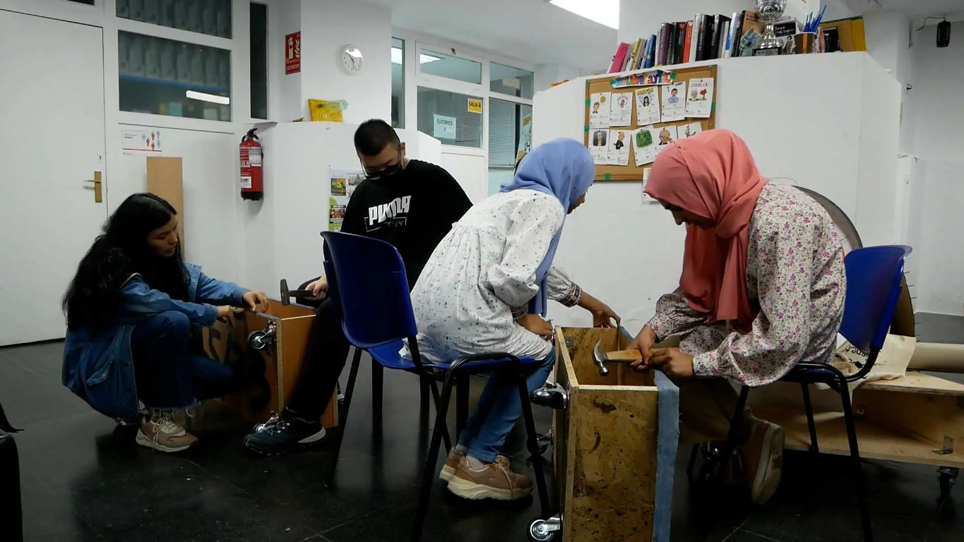 Nois i noies forren amb texans unes fustes que faran de sofàs.