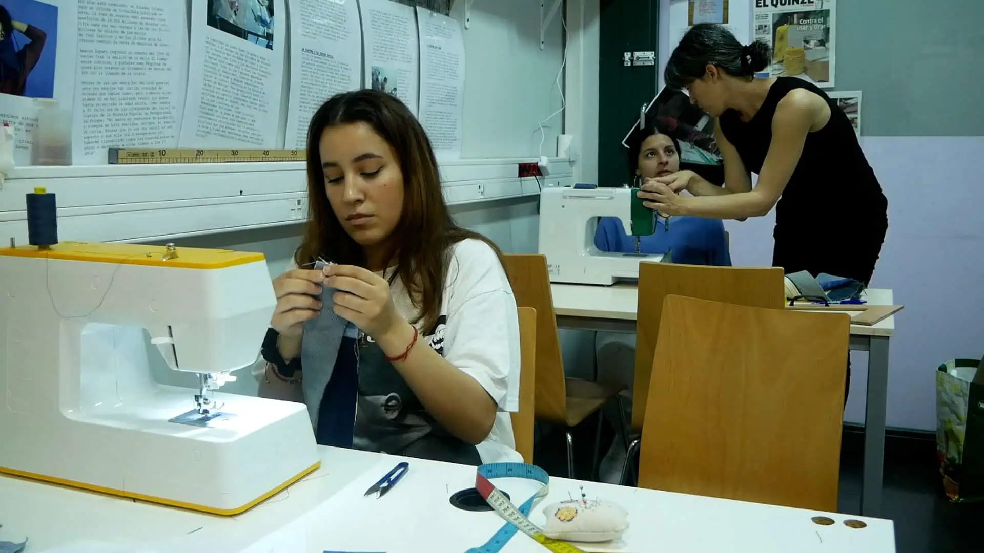 Noies cusen texans reciclats amb màquines de cosir.