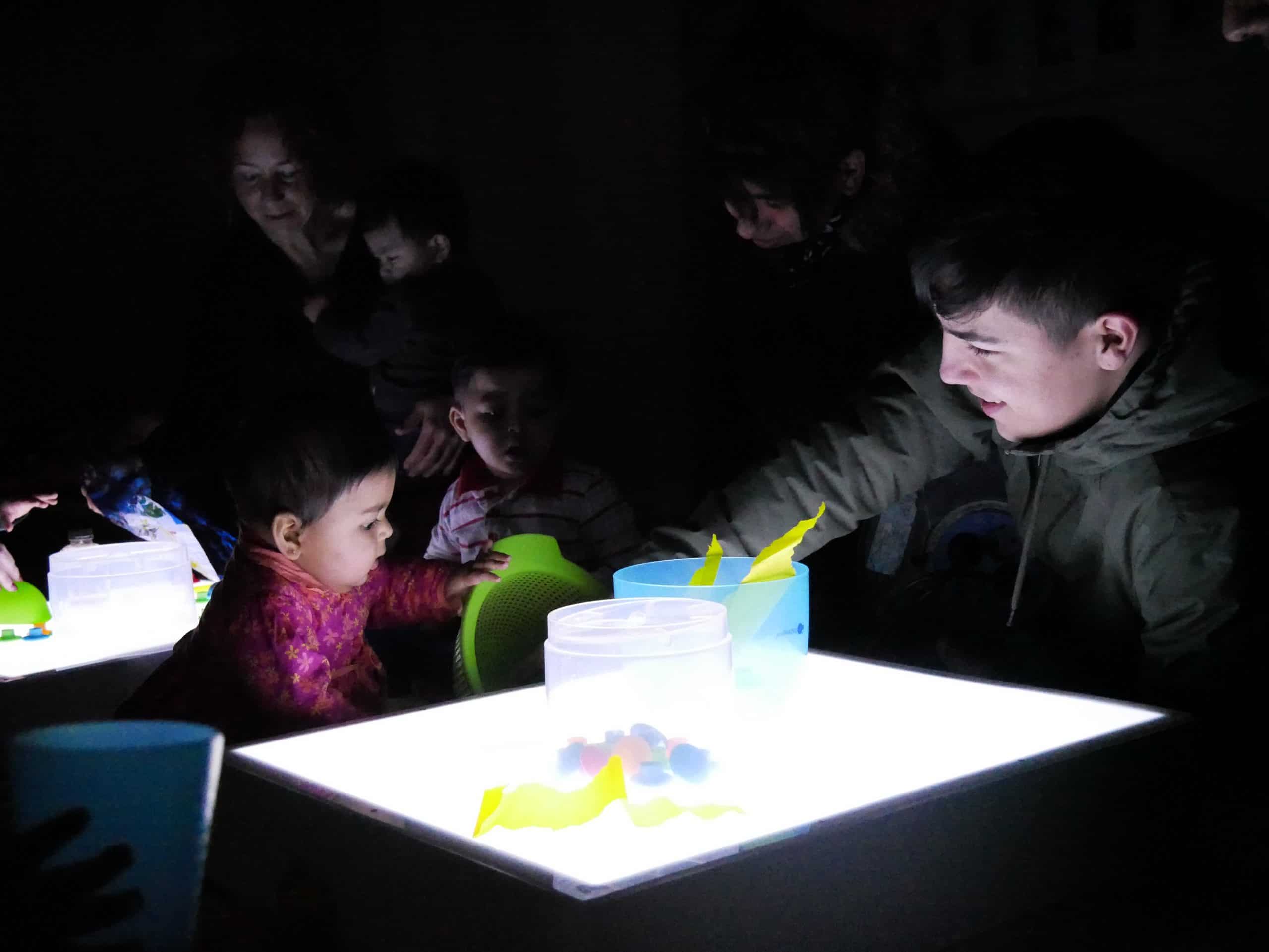 Nens jugant a les taules de llum fetes pels joves del Programa de Formació Inicial (PFI)