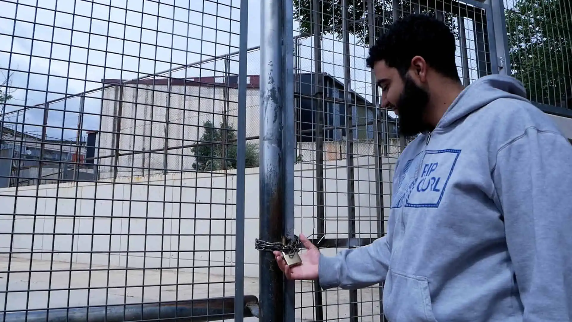 Noi es mira el candau que tanca la pista esportiva de Santa Coloma de Gramenet.